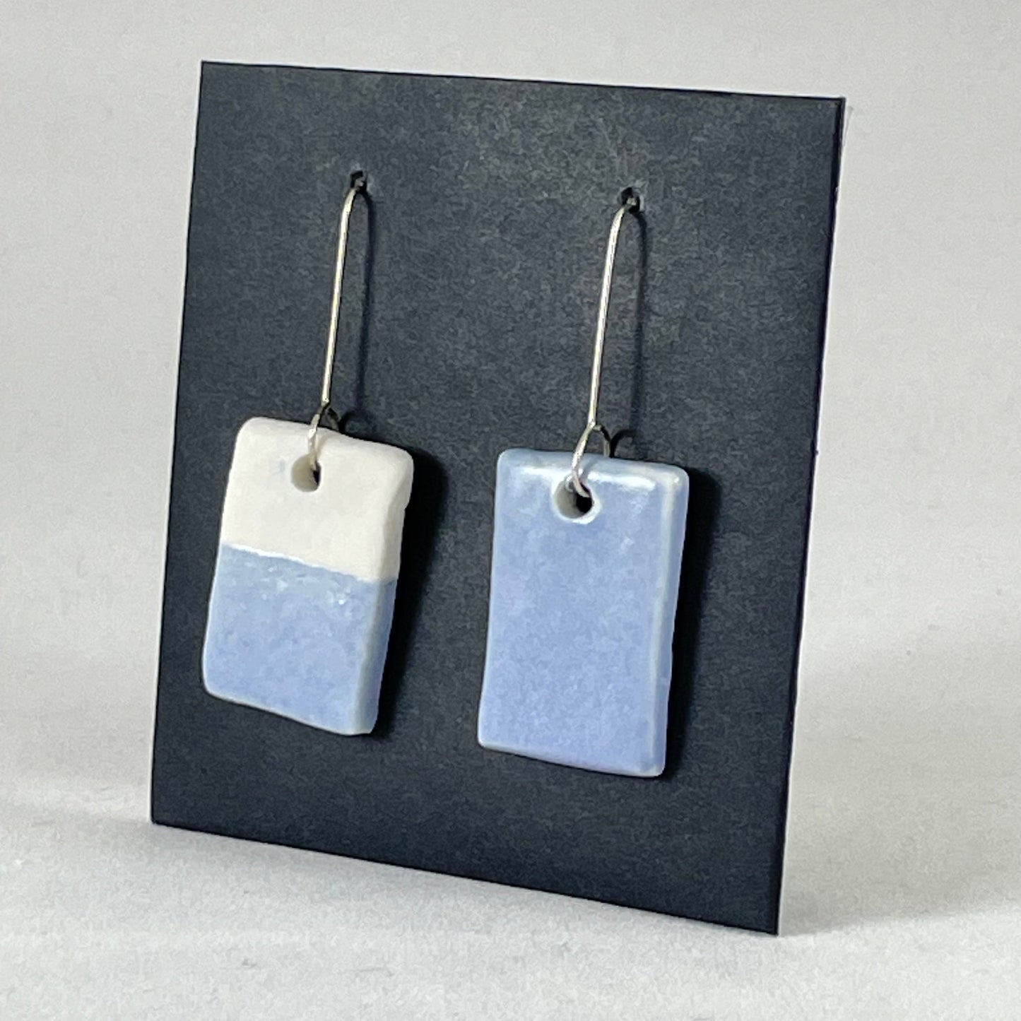 A pair of hand formed porcelain earrings in delicate blue and white. Side view showing thin earring profile