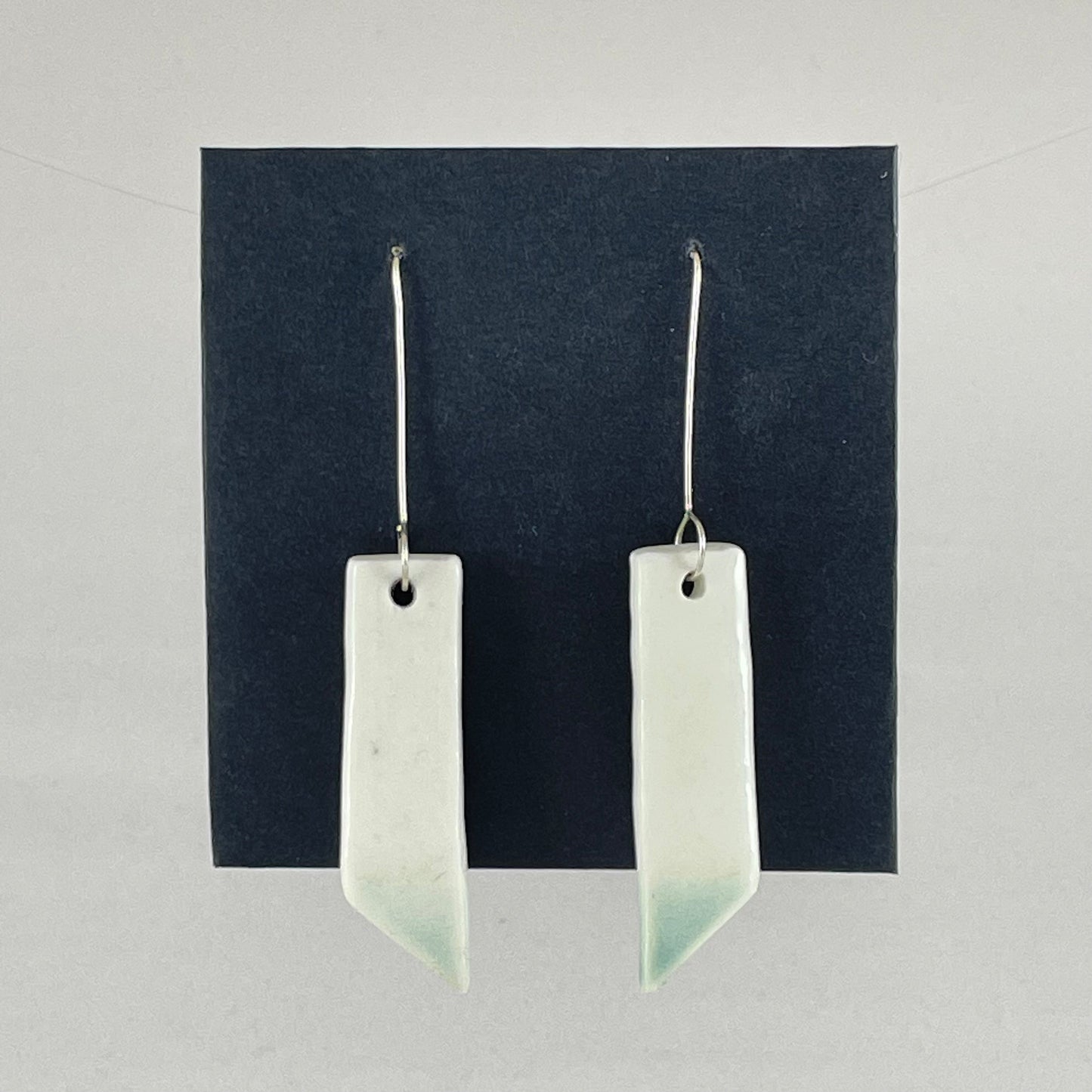 A pair of hand formed porcelain pendant earrings in glossy white and a hint of mint green