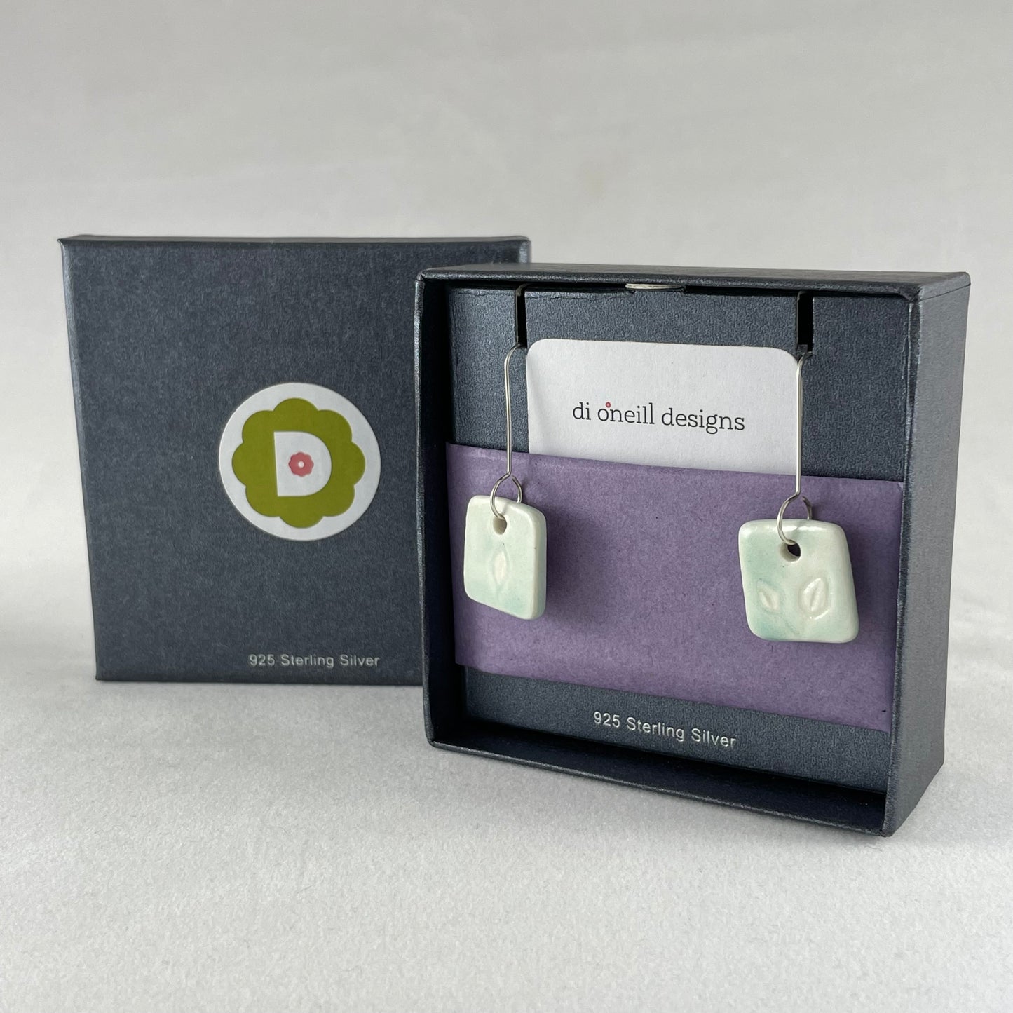 A pair of mint green square porcelain earrings in a jewellery box with tissue paper. On sterling silver earrings hooks.