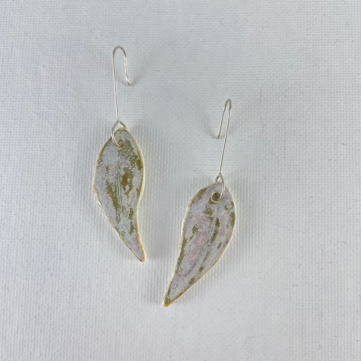A pair of porcelain earrings in organic gum leaf shape. Photographed on a white background.