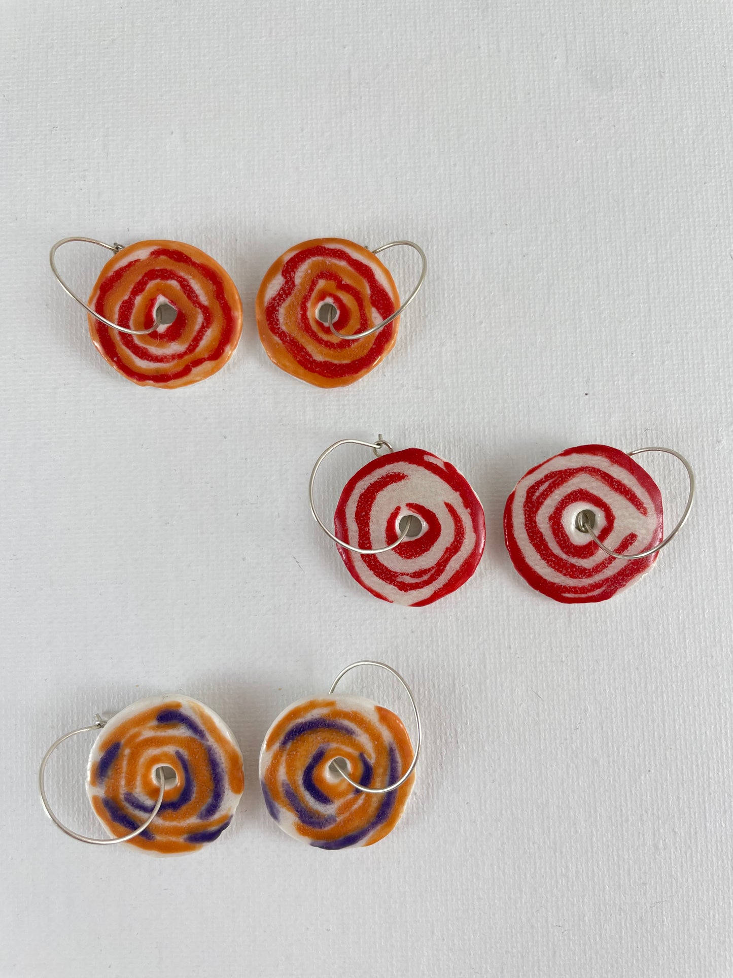 Three pairs of porcelain earrings on a white background. All pairs in simple rose pattern but different colours