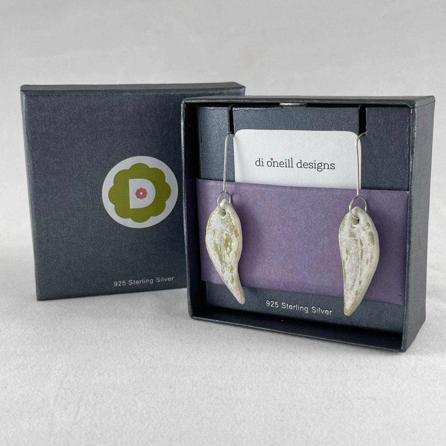 A pair of porcelain earrings in organic gum leaf shape. Photographed in opened jewellery box with tissue paper