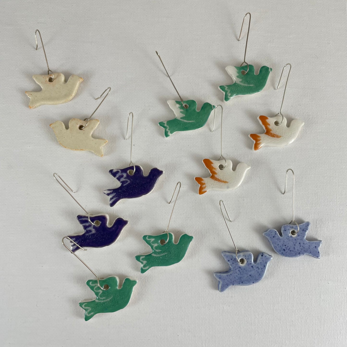 Six pairs of porcelain earrings in the shape of flying dove in different colours