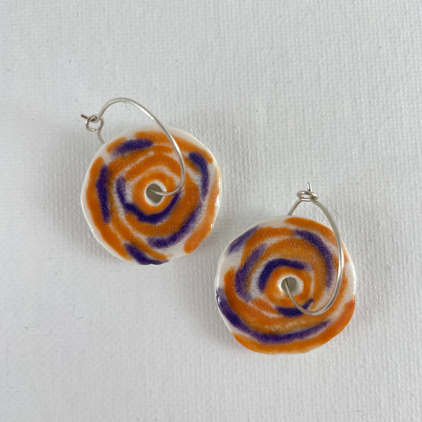 A pair of lavender and orange porcelain earrings on a white background. Simple rose pattern.
