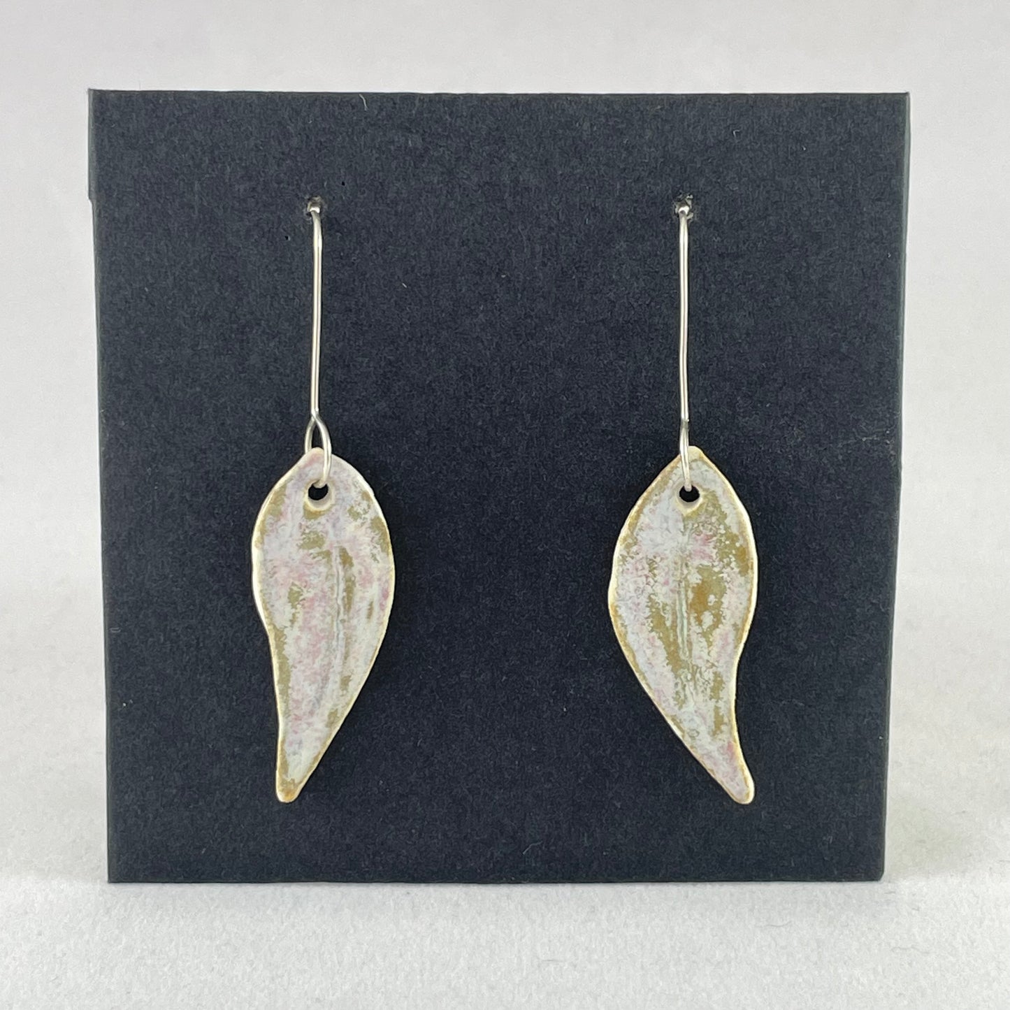 A pair of porcelain earrings in organic gum leaf shape. Photographed on a black background.