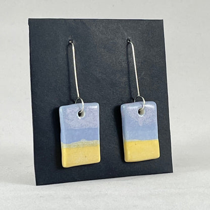A pair of hand formed porcelain pendant earrings in delicate blue and yellow. Side view showing thin earring profile
