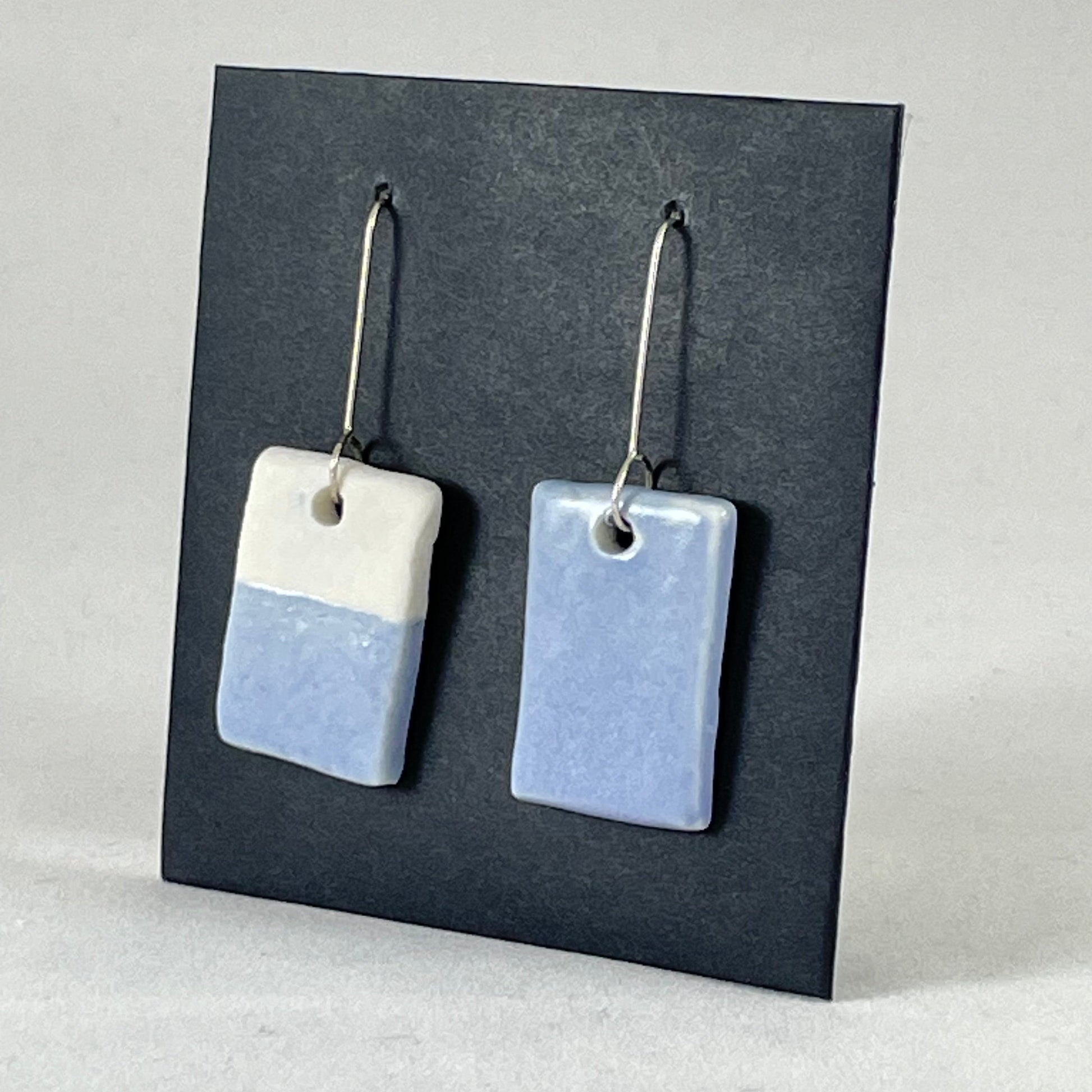 A pair of hand formed porcelain earrings in delicate blue and white. Side view showing thin earring profile