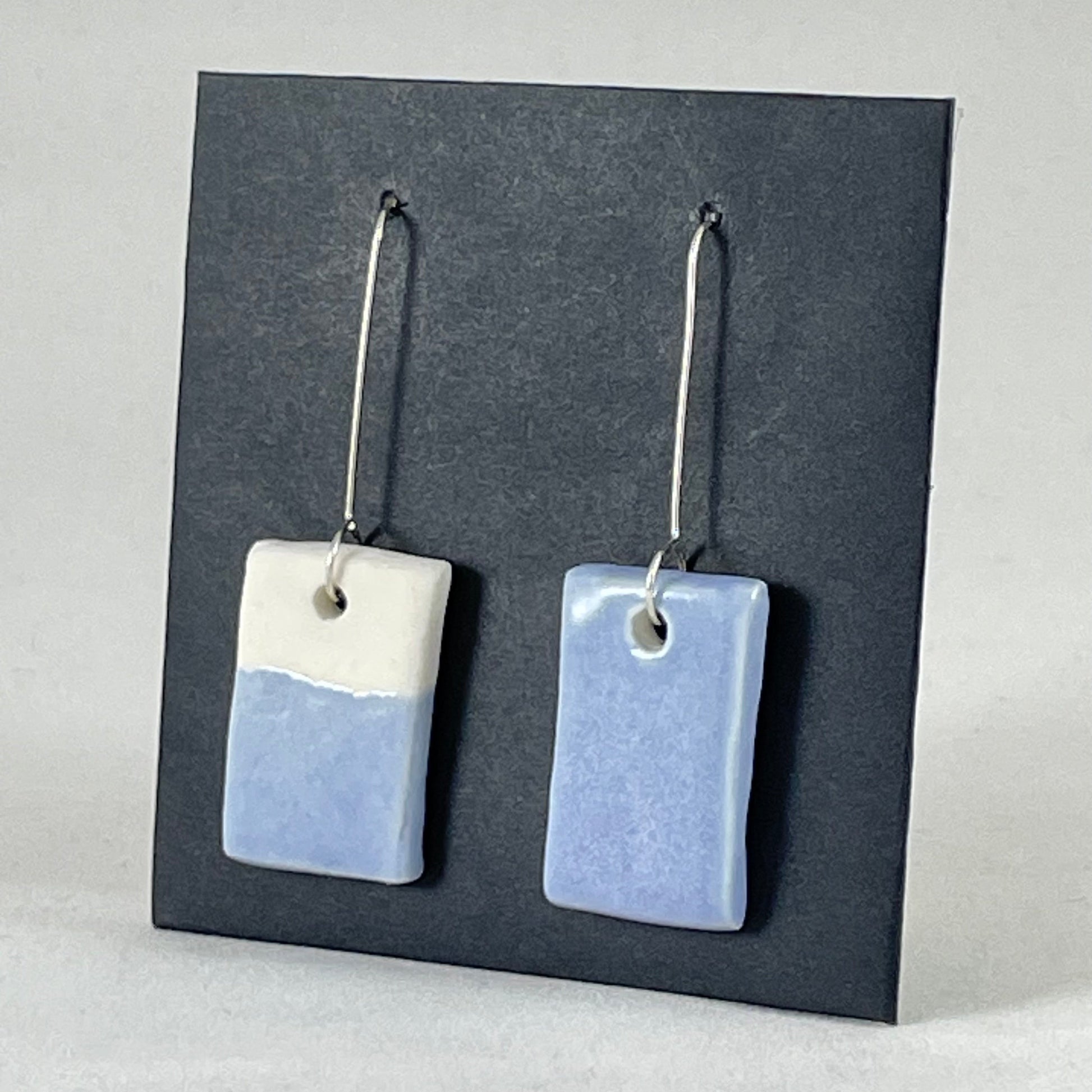A pair of hand formed porcelain earrings in delicate blue and white. Side view showing thin earring profile