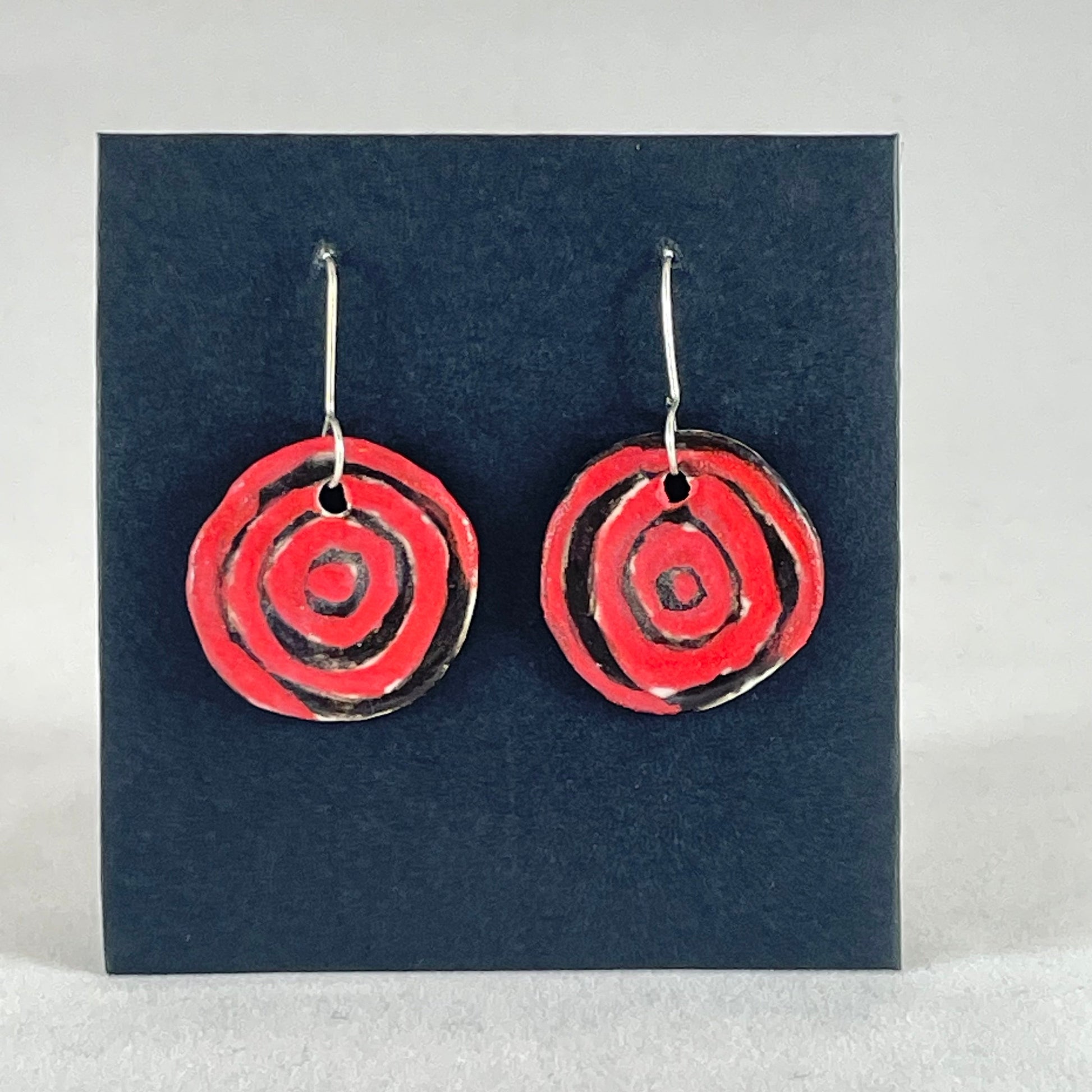 A pair of hand formed porcelain pendant earrings in striking black and red abstract flower pattern