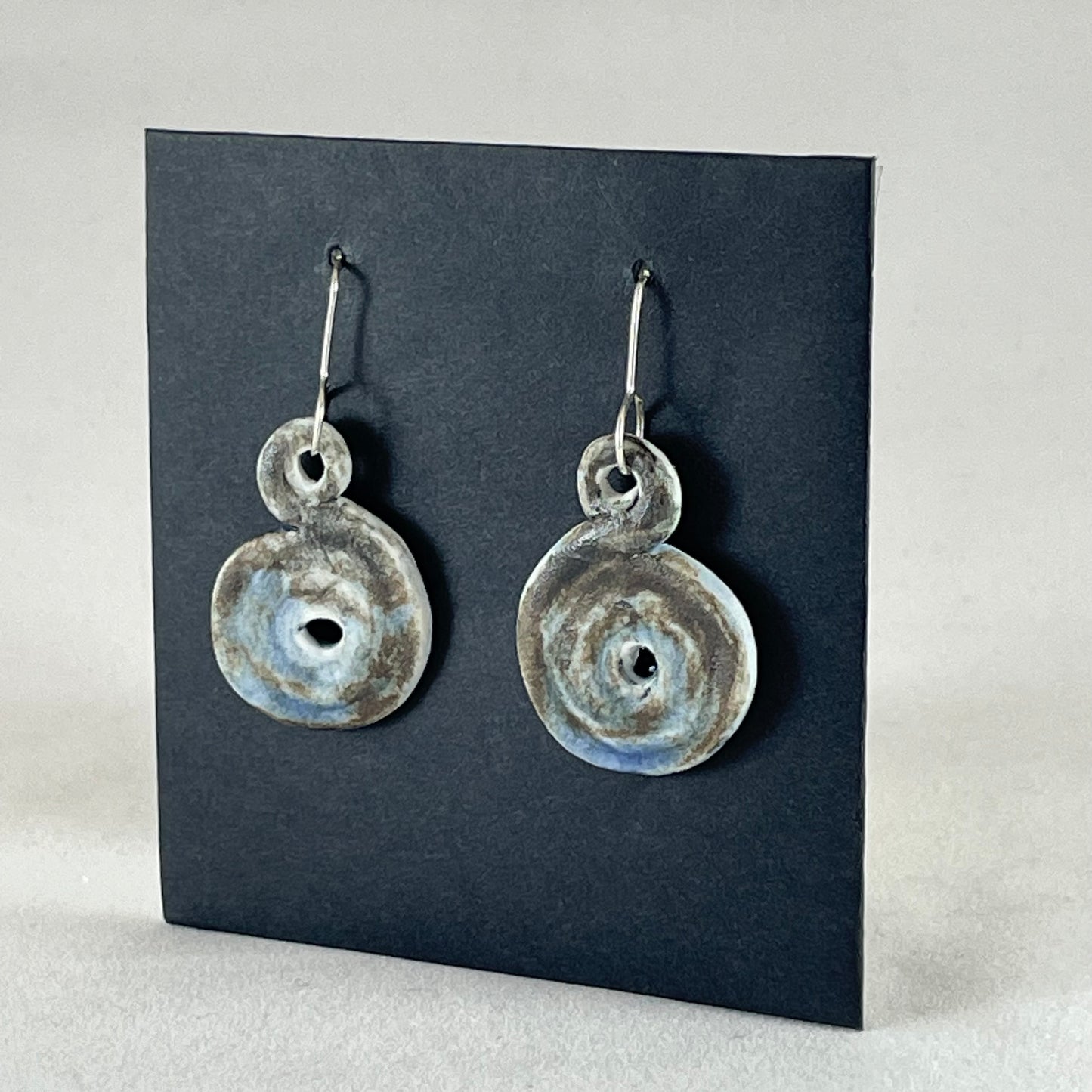 Pair of hand coiled pendant earrings. Blue brown and white textured pattern. Side view