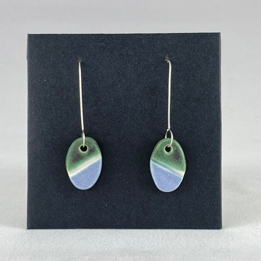 A pair of green, white and lilac-blue earrings on a black background. 