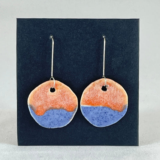 A pair of circular shaped porcelain earrings in blue and orange. On sterling silver earrings hooks. 