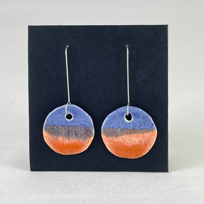 A pair of circular shaped porcelain earrings in blue and orange. On sterling silver earrings hooks. 