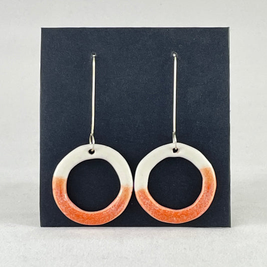 A pair of hoop shaped porcelain earrings in white and orange. On sterling silver earrings hooks. 