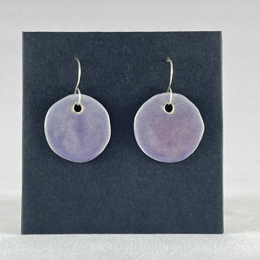 A pair of circular shaped porcelain earrings in purple. On sterling silver earrings hooks.