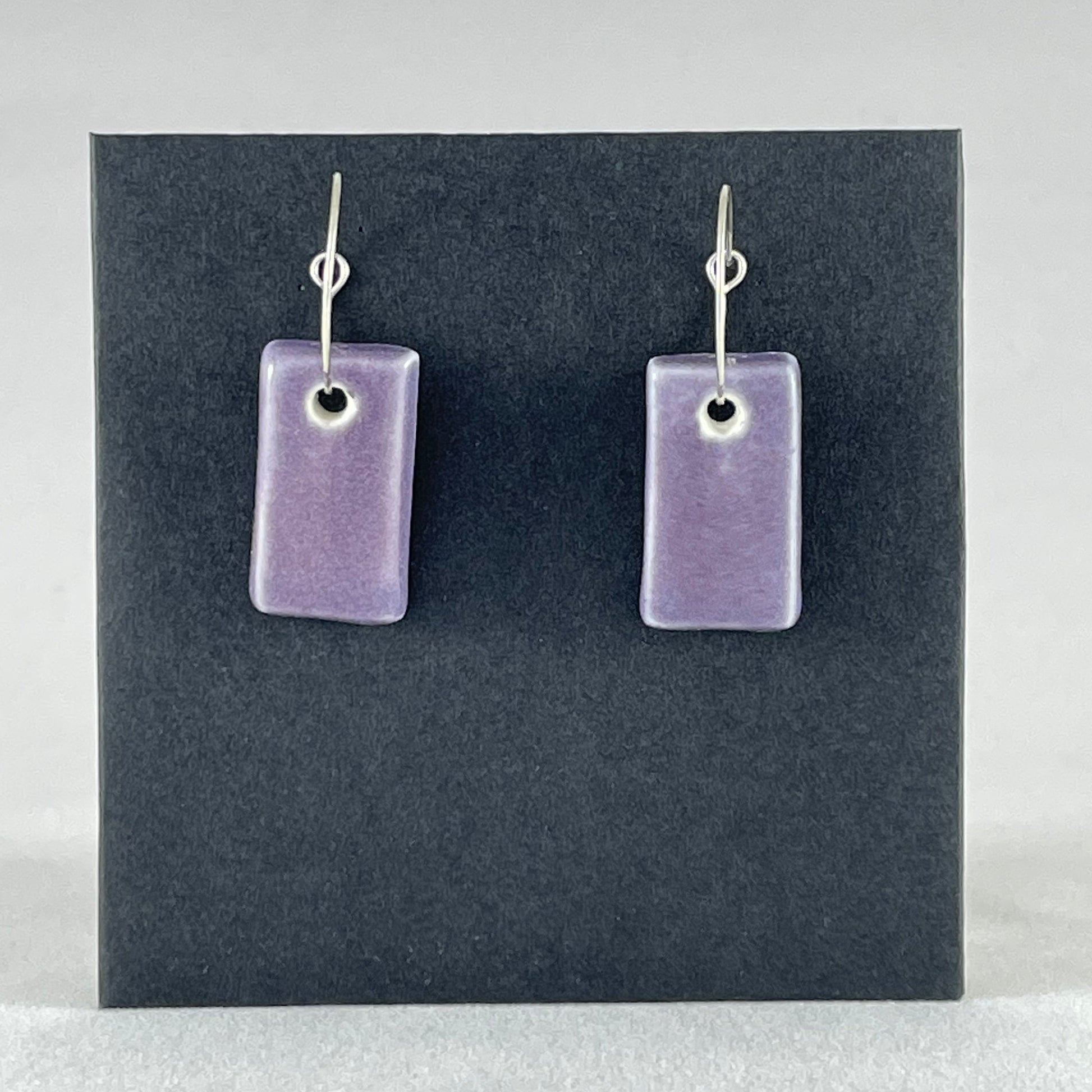 A pair of rectangular shaped porcelain hoop earrings in purple. On sterling silver earrings hooks.
