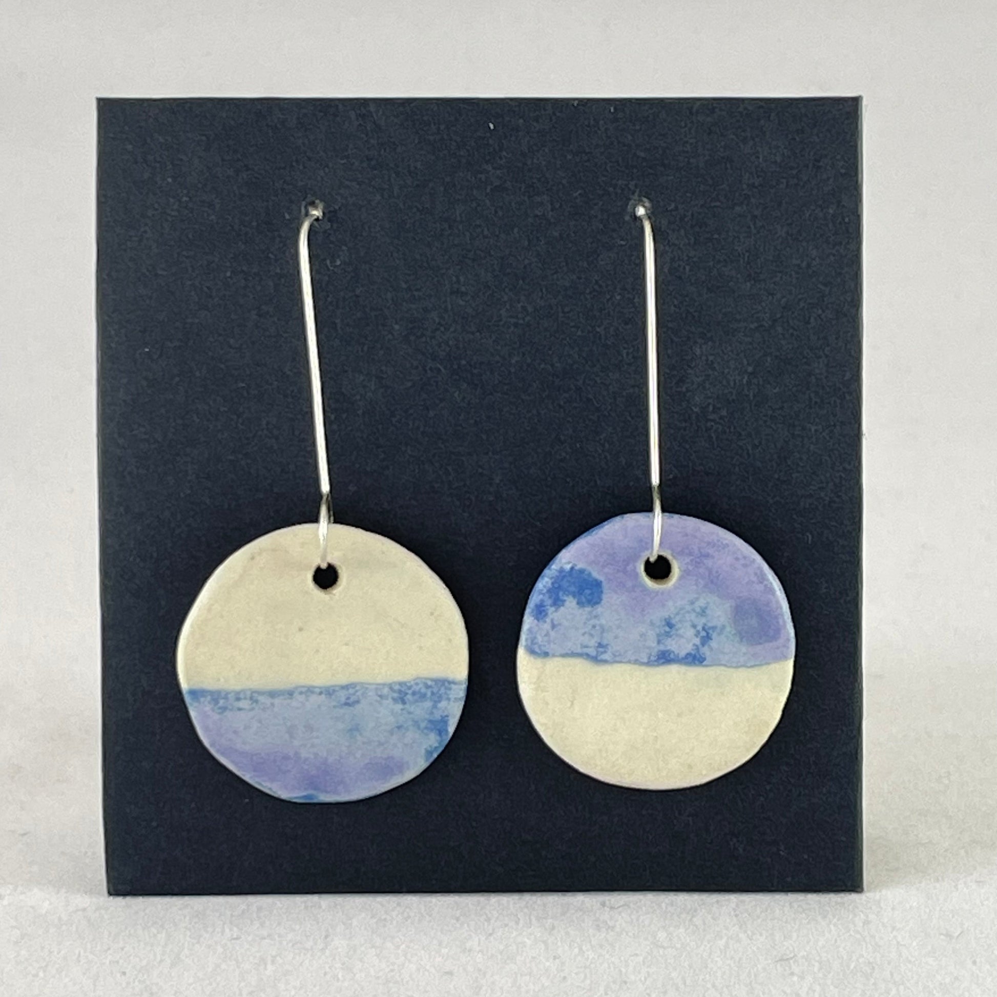 A pair of circular shaped porcelain earrings in blue and white. On sterling silver earrings hooks.