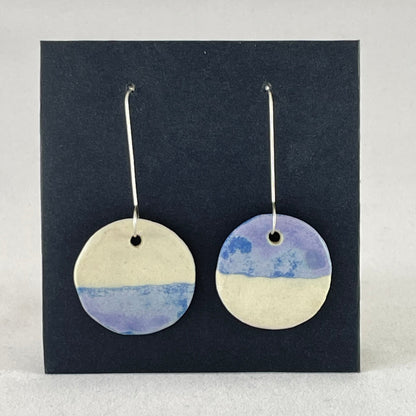 A pair of circular shaped porcelain earrings in blue and white. On sterling silver earrings hooks.