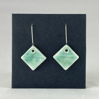 A pair of diamond shaped porcelain earrings in green. On sterling silver earrings hooks.