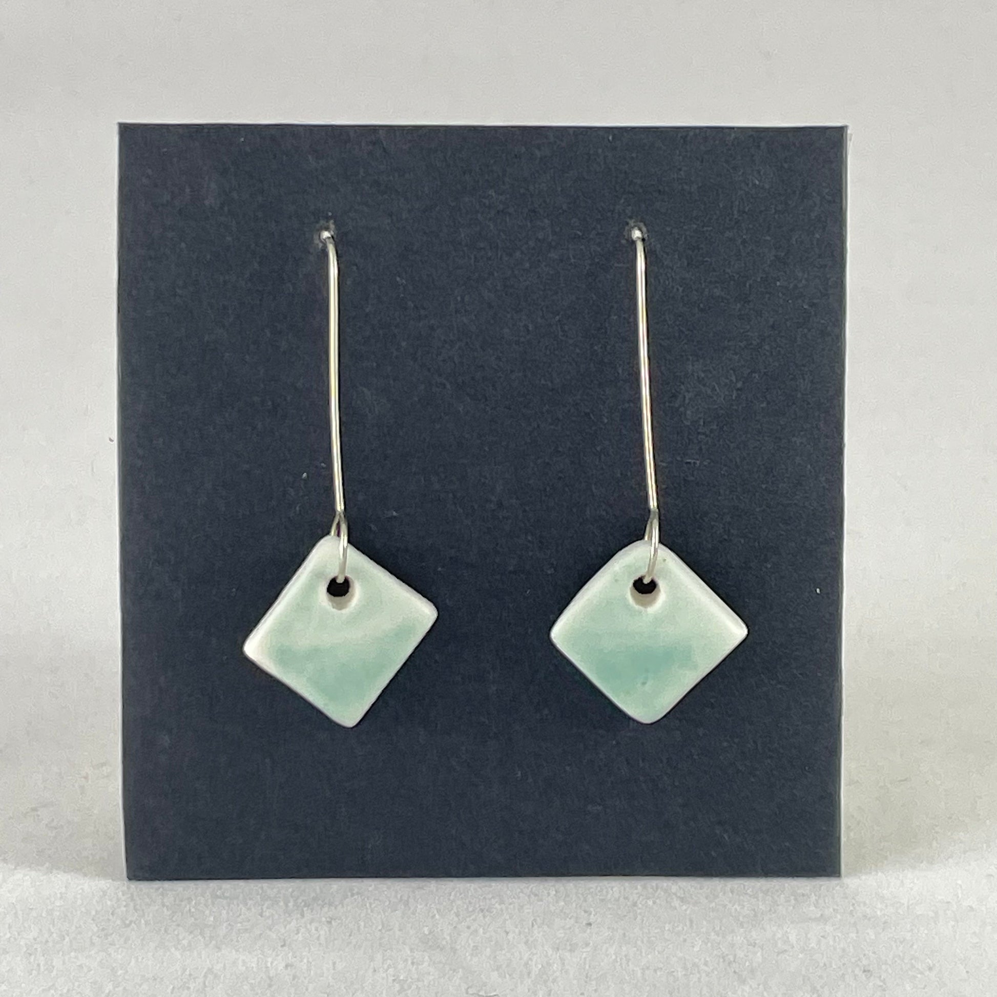 A pair of diamond shaped porcelain earrings in green. On sterling silver earrings hooks.
