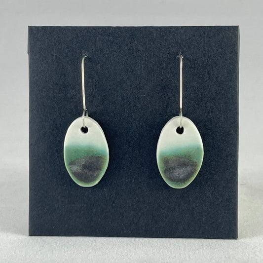 Pair of emerald green and white oval shaped porcelain earrings. Top half white and bottom half textured green. Sterling silver hooks.