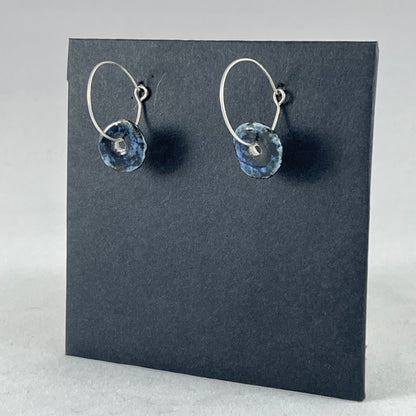 A pair of blue hand coiled porcelain earrings on sterling silver hoops. Photographed on a graphite coloured background. Side view