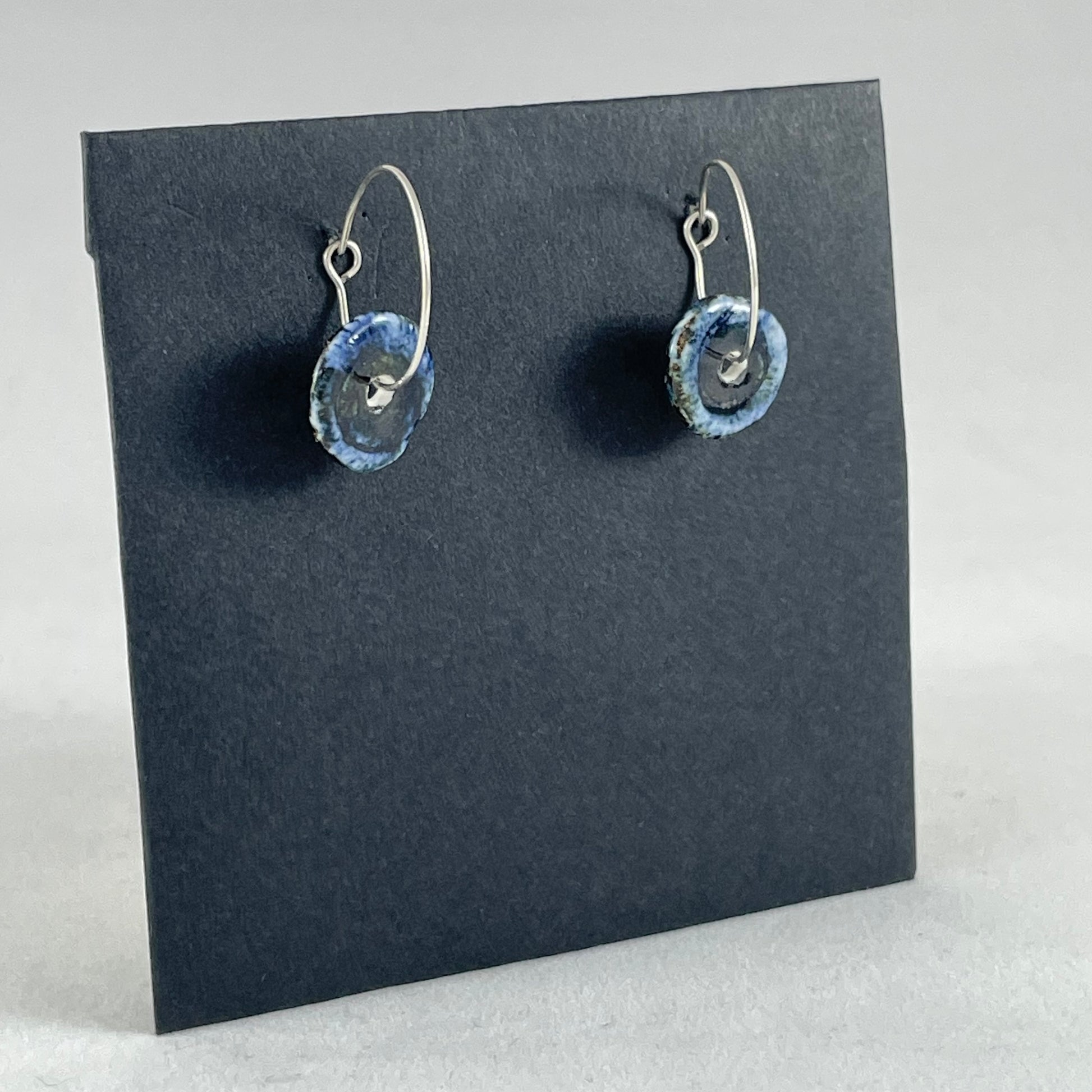 A pair of blue hand coiled porcelain earrings on sterling silver hoops. Side view