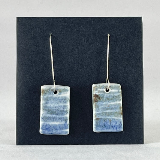 A pair of blue green and white porcelain earrings. Photographed on a black background. On sterling silver earrings hooks. 