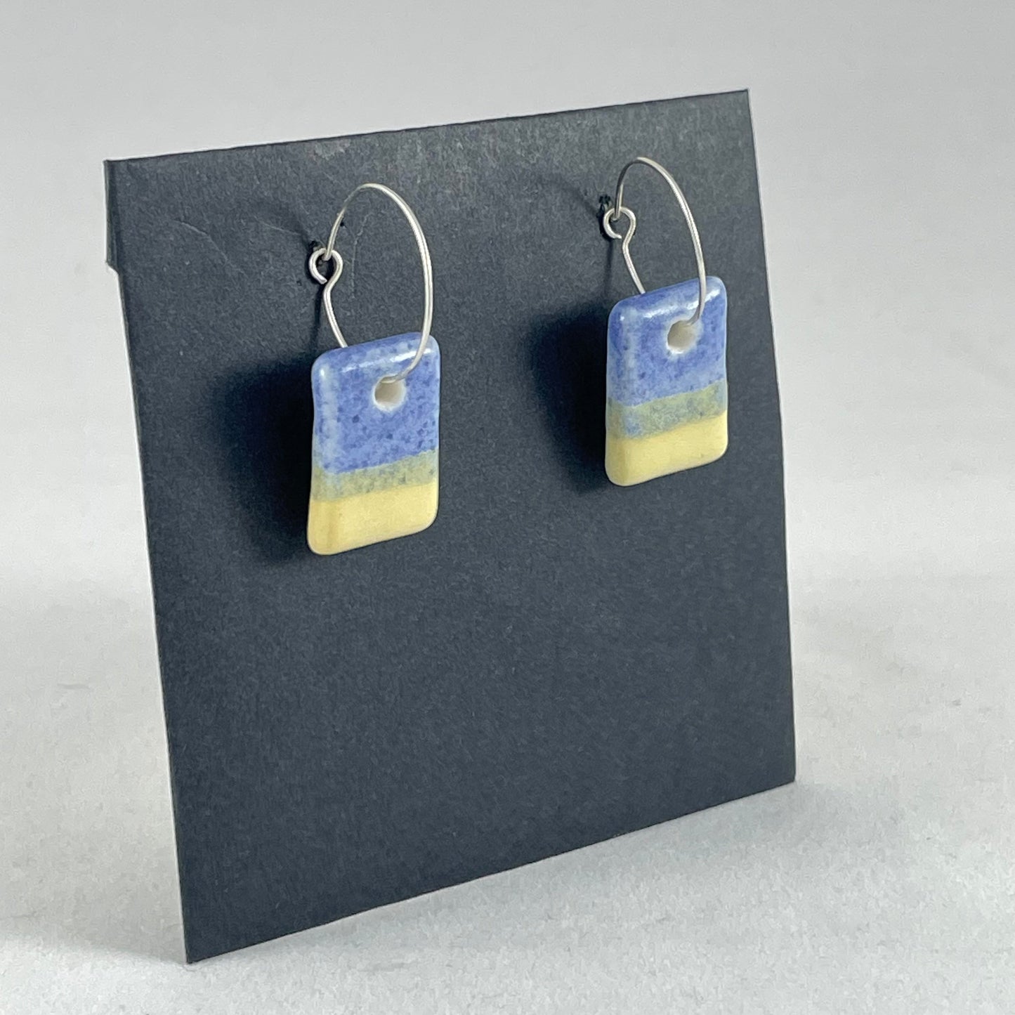 A pair of porcelain earrings in yellow and blue. Cute rectangular pendant on sterling silver hooks. Side view