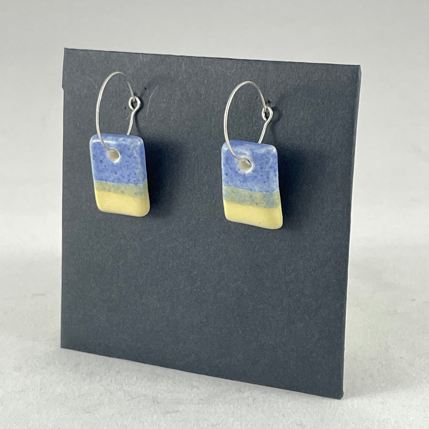 A pair of porcelain earrings in yellow and blue. Cute rectangular pendants on sterling silver hooks. Side view