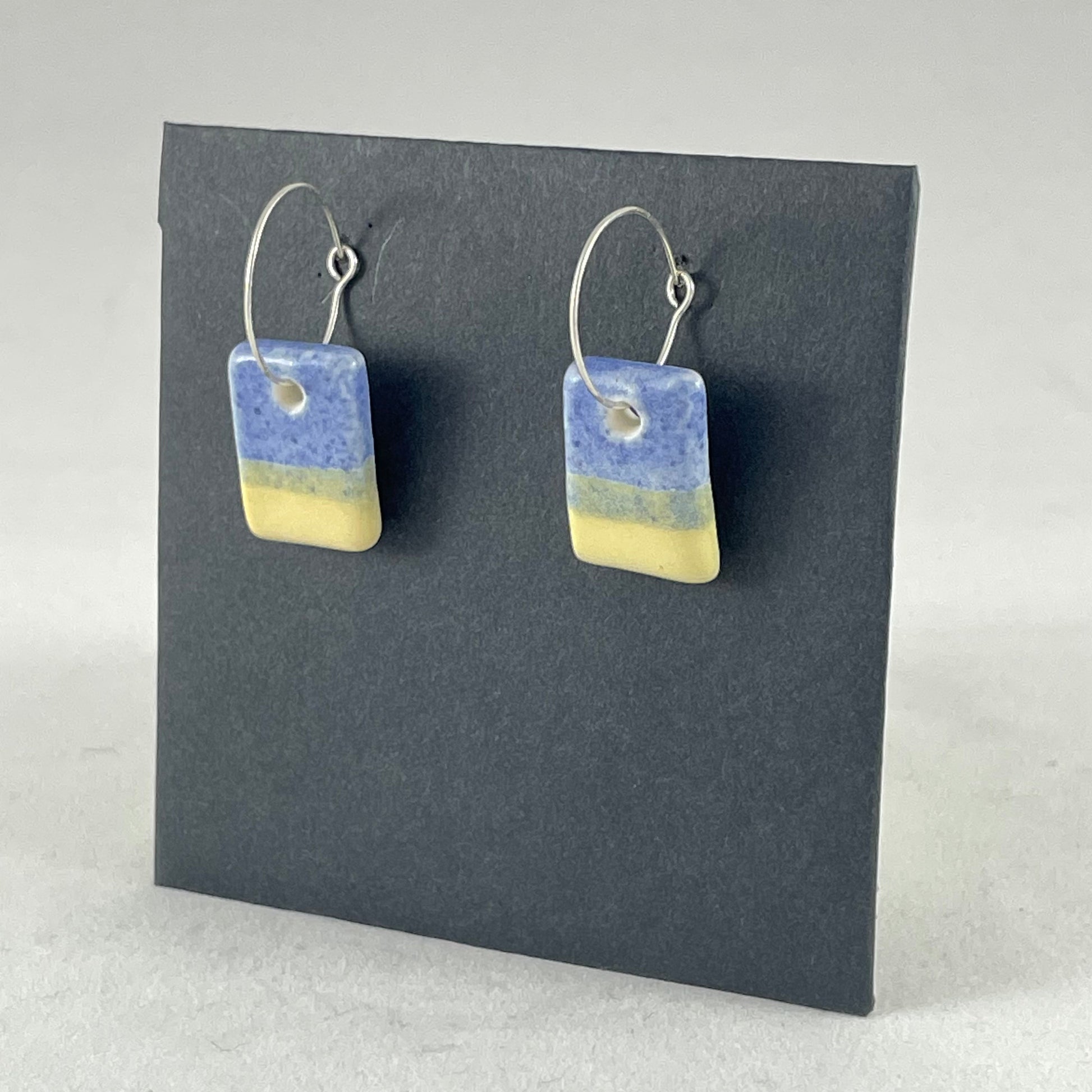 A pair of porcelain earrings in yellow and blue. Cute rectangular pendants on sterling silver hooks. Side view