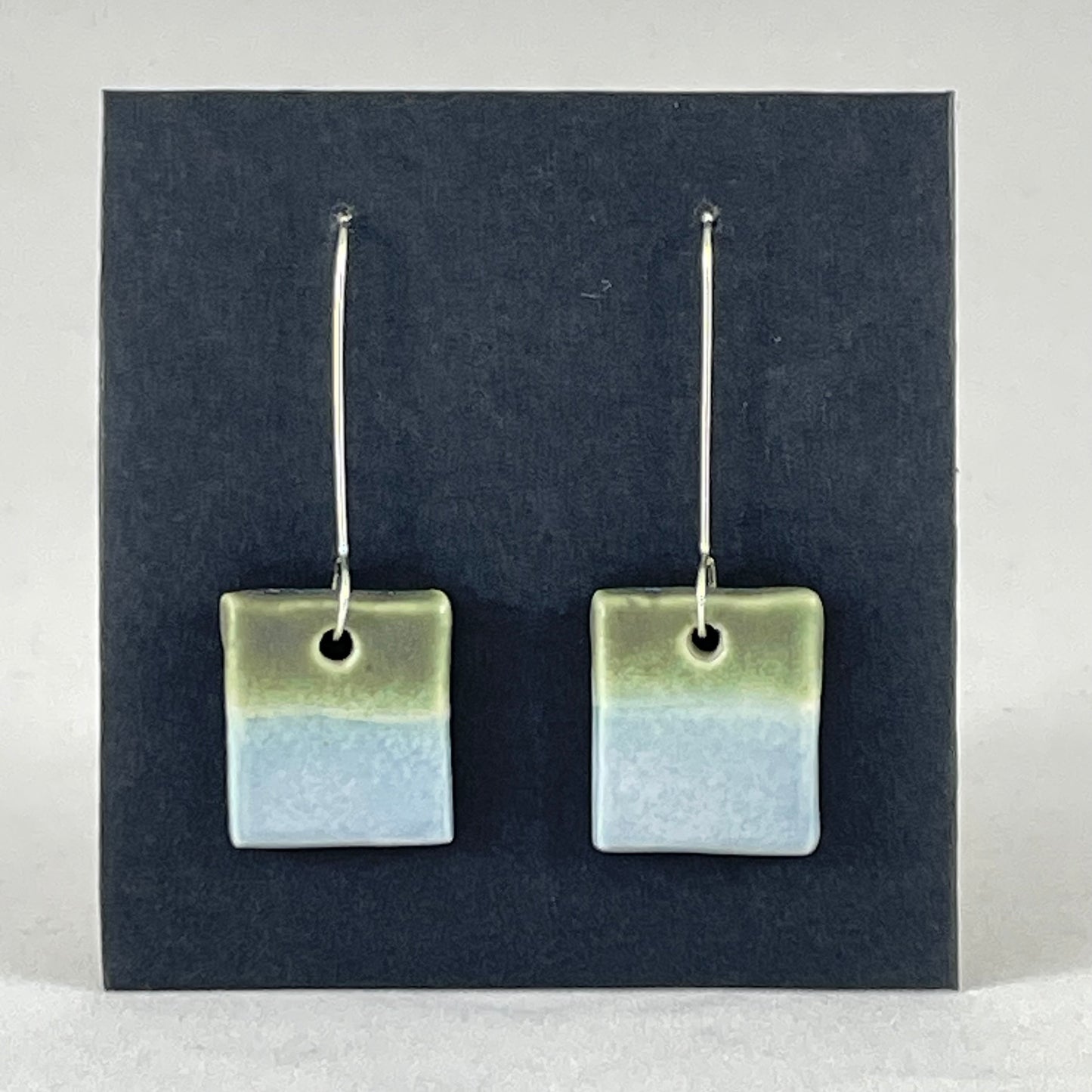 A pair of square shaped porcelain earrings in blue and green. On sterling silver earrings hooks.
