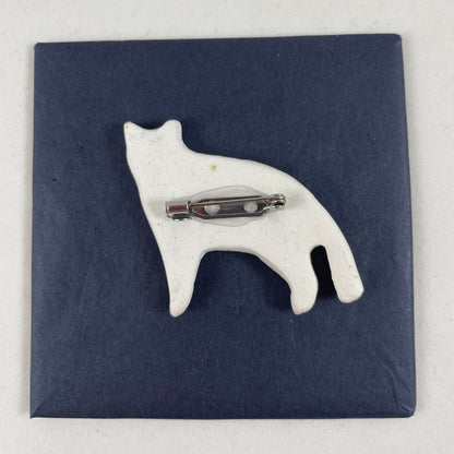 Back view of brooch. White unglazed porcelain with stainless steel brooch fastening glued on.
